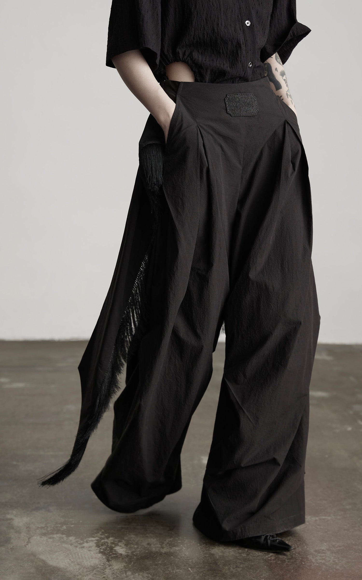 DOINDULGE Wide-Leg Draped Pants with Fringed Panels and Deconstructed Details
